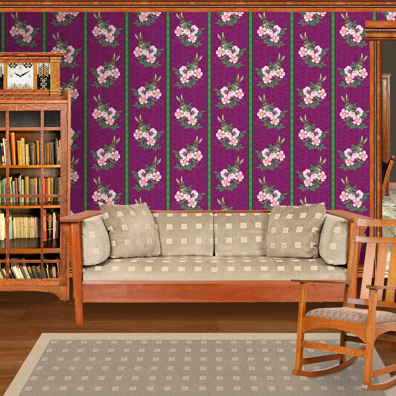 The artwork depicts a stylized brown hare partially concealed behind a cluster of green leaves and pink flowers with yellow centers. The background is dark green with subtle leafy patterns. Two vertical stripes—one dark purple and one green with small floral motifs—run along the left side, contrasting with the otherwise naturalistic elements. The composition balances the lively flora and fauna with a decorative, patterned design. The wallpaper design is shown in a Mission style living room